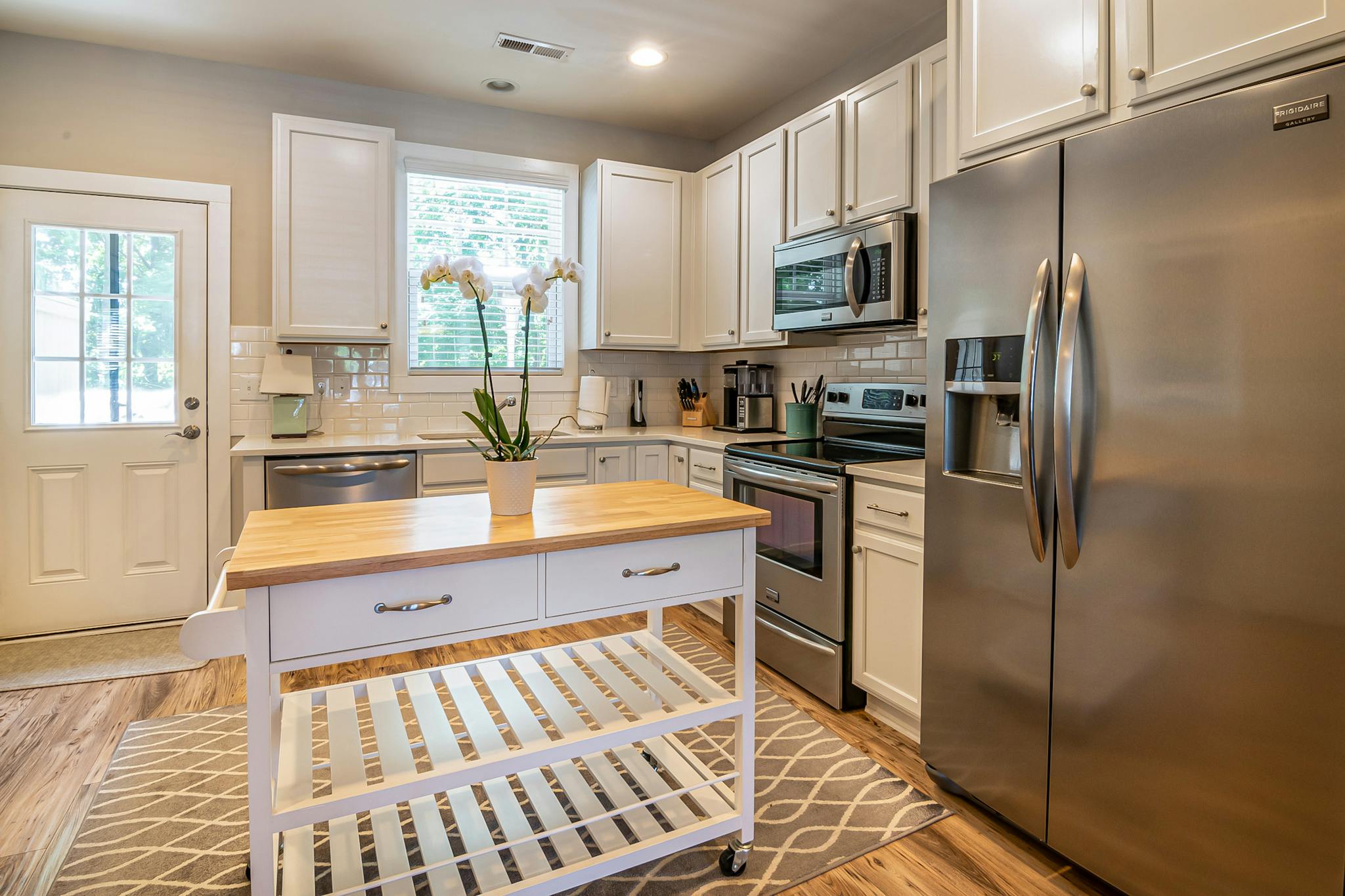 Spacious kitchen featuring stainless steel appliances and island with wooden countertop.